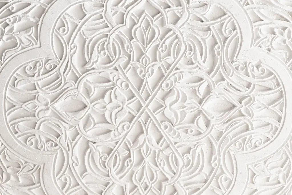 Zierstuck Nahaufnahme eines weißen, symmetrisch ornamentalen Zierstücks mit floralen und geometrischen Mustern