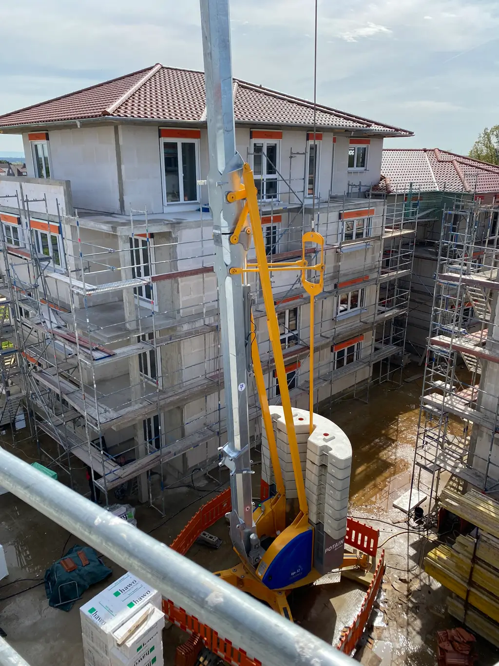 Mehrstöckiges Gebäude im Rohbau mit Gerüst und Bauaufzug auf einer Baustelle