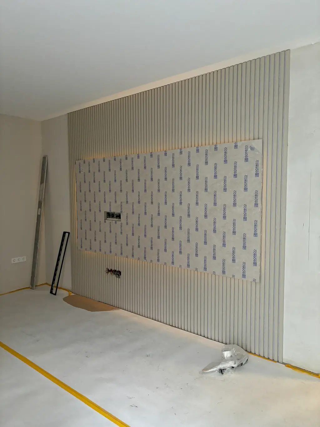 Raum mit halbfertiger Trockenbauwand, vertikale Holzlatten und mittig montierte Gipskartonplatte mit Aufdruck