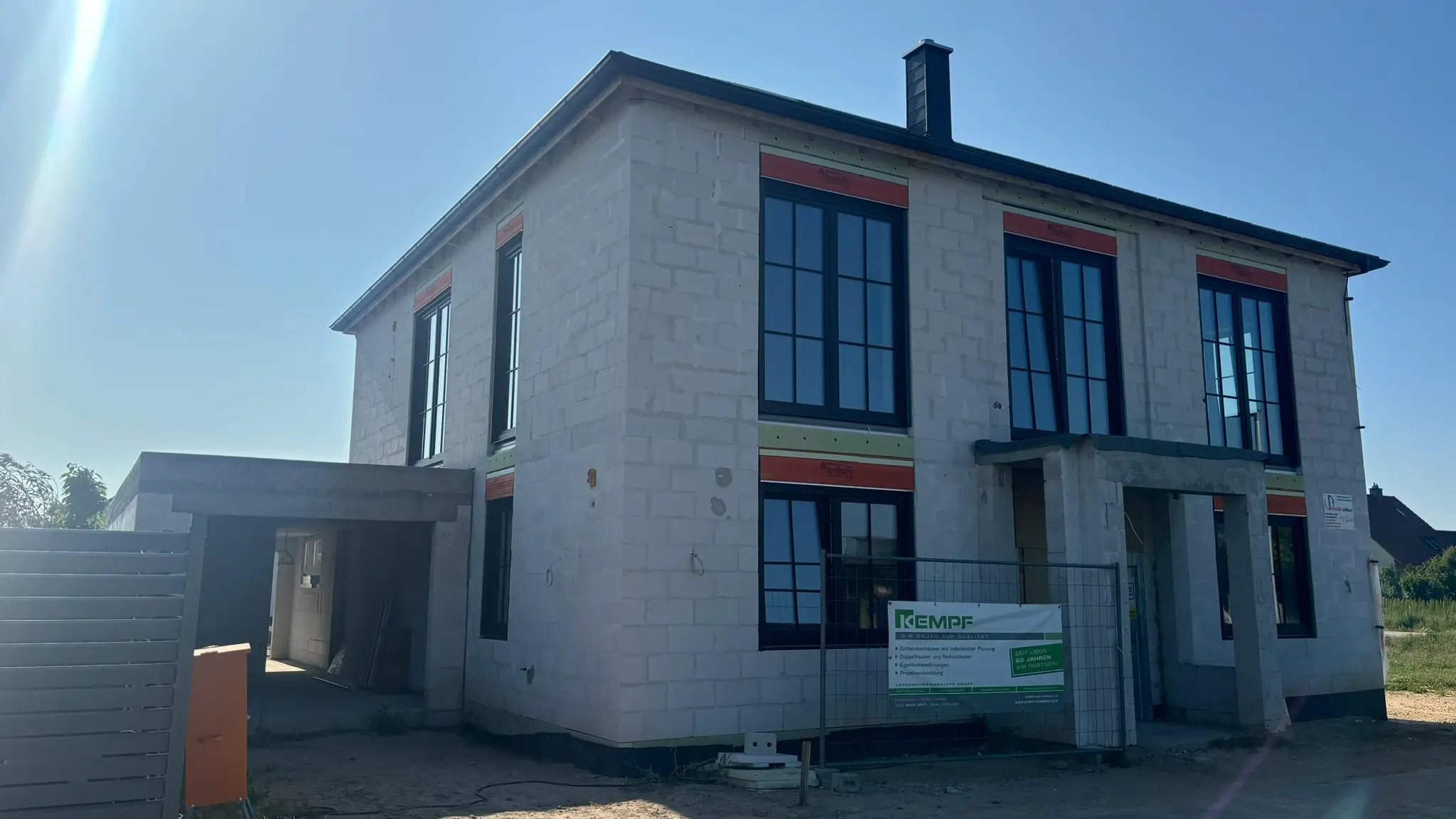 Verputzung-Hausfassade Unfertiges zweistöckiges Haus mit verputzter Fassade und großen Fenstern bei Tageslicht